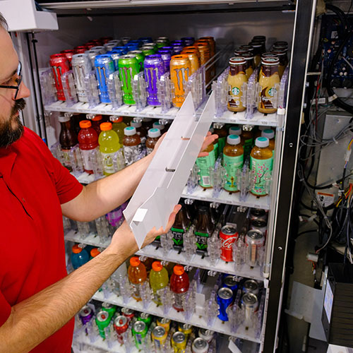 a vending machine operator adjusts shelves in a vending machine